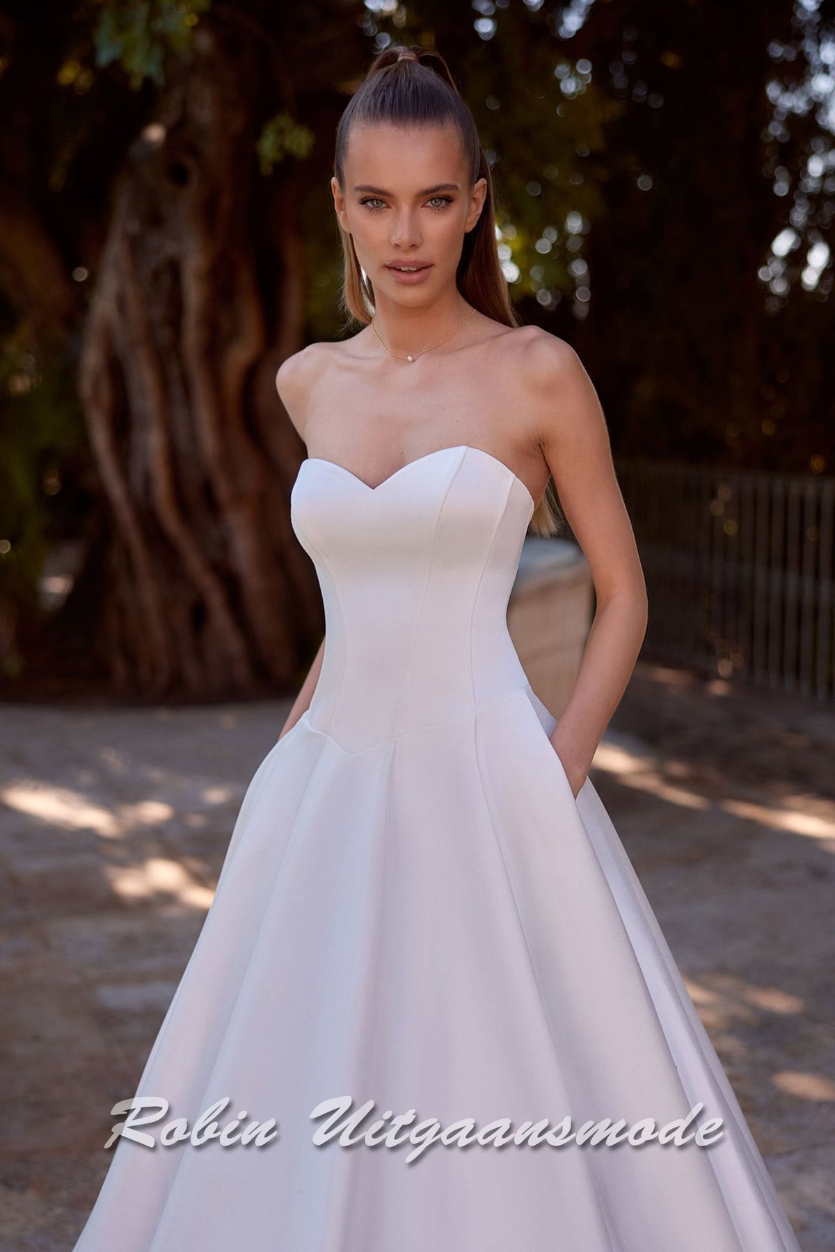 Close-up van de Strapless trouwjurk met lage taille, een A-lijn rok met verborgen zakken en kathedraal sleep