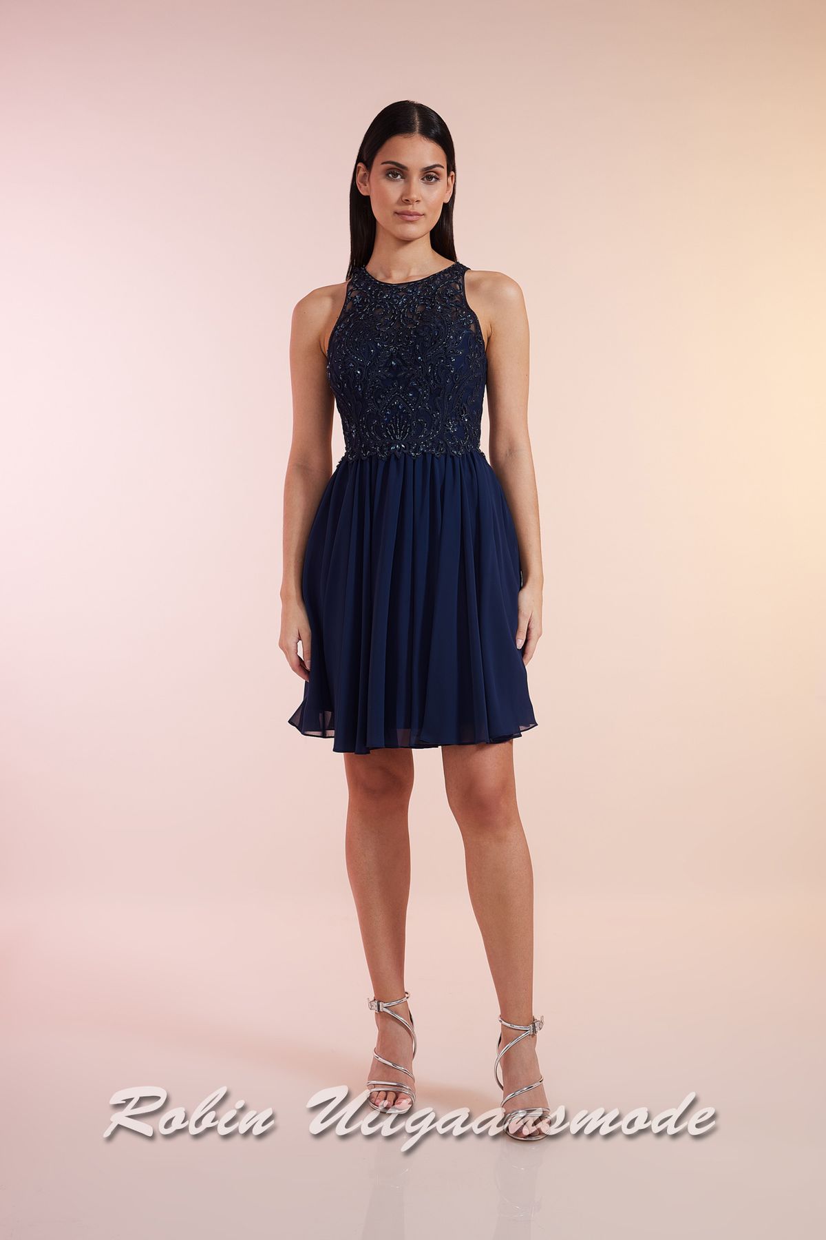 Navy blauwe cocktailjurk met hooggesloten kanten lijfje, blote schouders en een geplooide chiffon rok tot net boven de knie