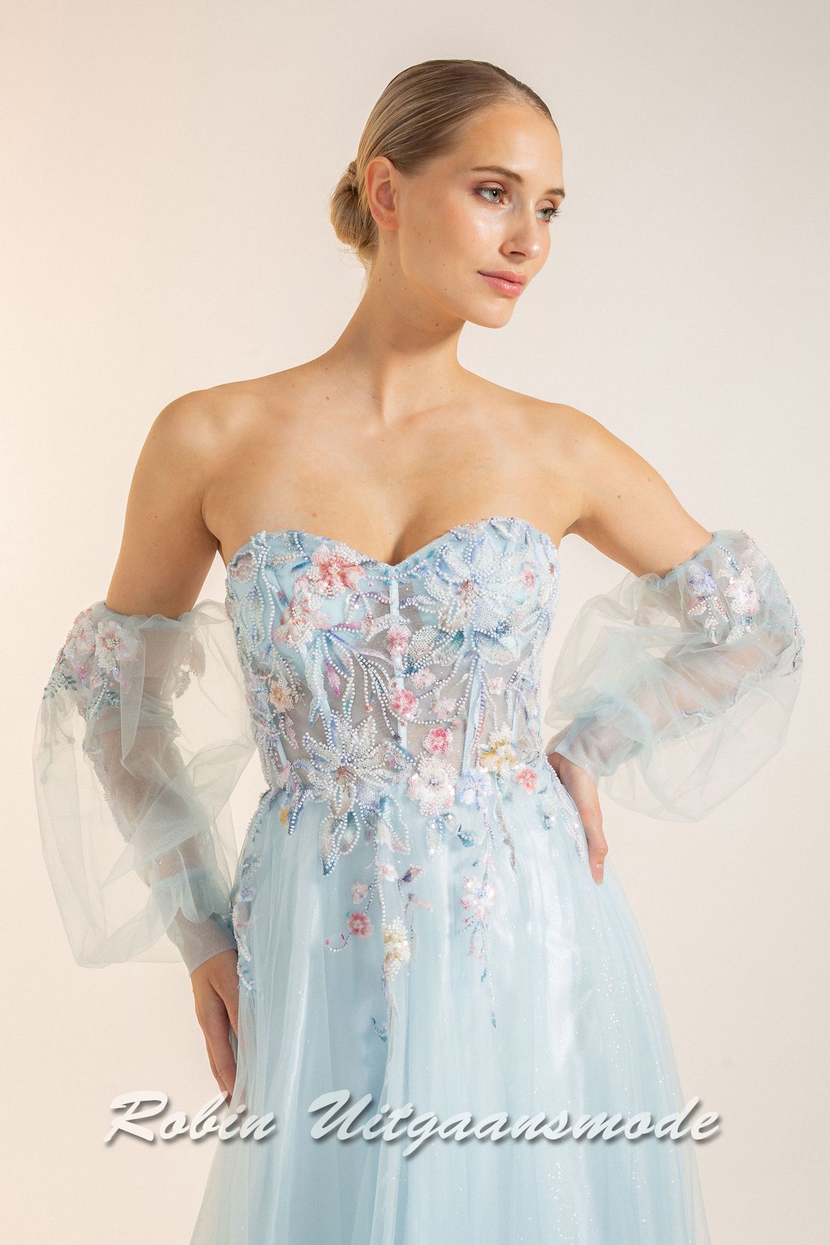 Close-up van de Strapless lichtblauwe galajurk met bloemen lijfje, losse pofmouwen van tule en springerige rok van soft tule