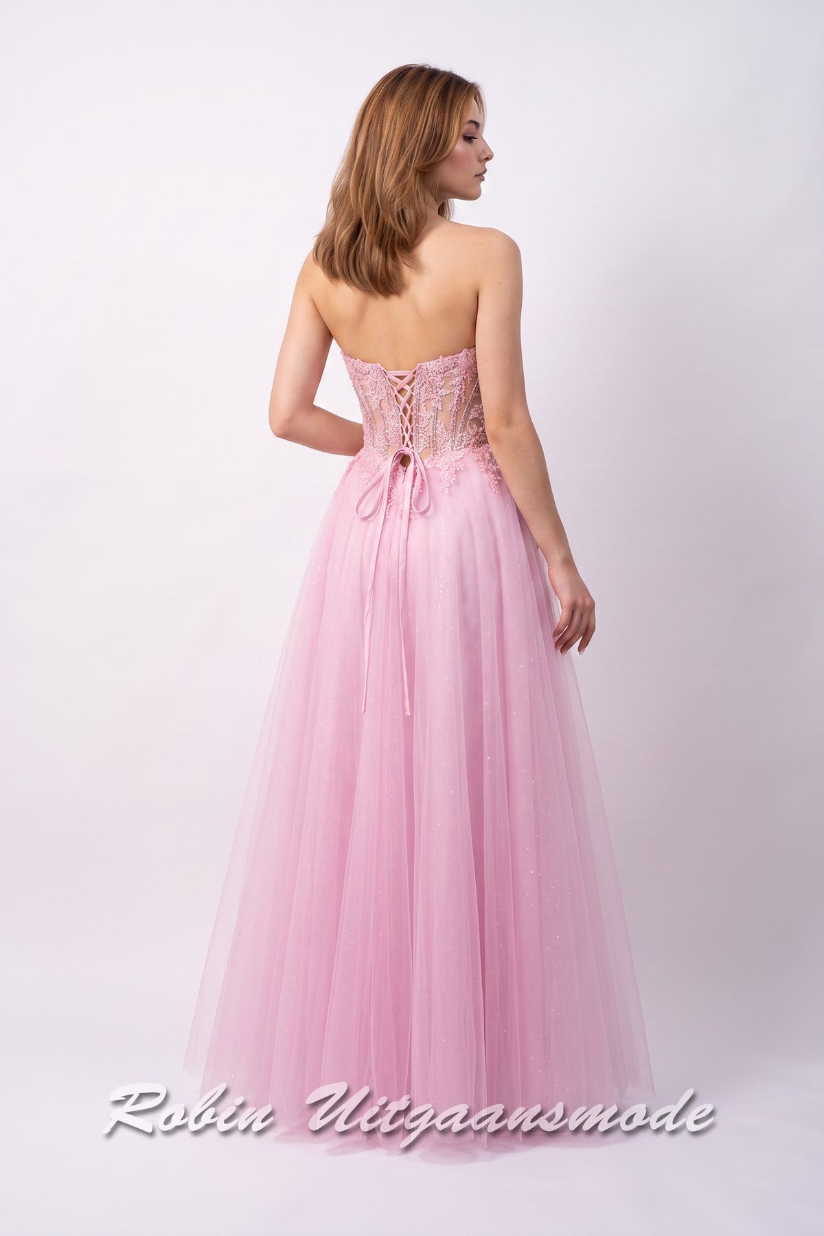 Achterkant van de Lichtroze galajurk strapless korset lijfje, fleurige bloemversiering over de top en  A-lijn tule rok met hoge split
