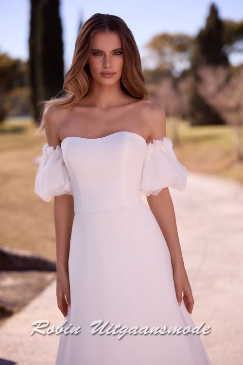 Close-up van de Strapless trouwjurk met een heartshape halslijn, losse pofmouwtjes van chiffon en een A-lijn rok met lange sleep