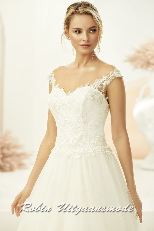 Het hart shaped lijfje is fraai bedekt met kant, welke doorloopt in de off-shoulder banden naar het rugpand