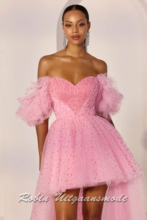 Close-up van de roze Kort-lange galajurk bedekt met hartjes en ruche off-shoulder top